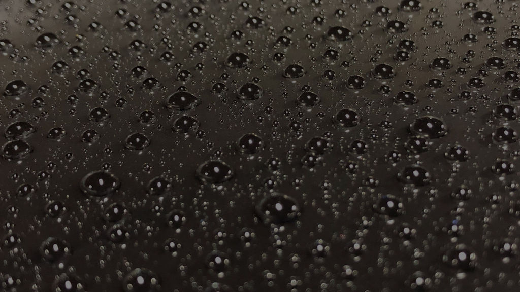Rain water beading and rolling off a ceramic coated paint surface